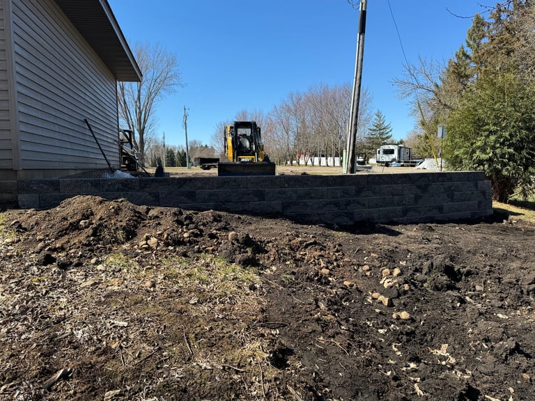Construction site with bulldozer pushing dirt pile next to concrete foundation and residential building