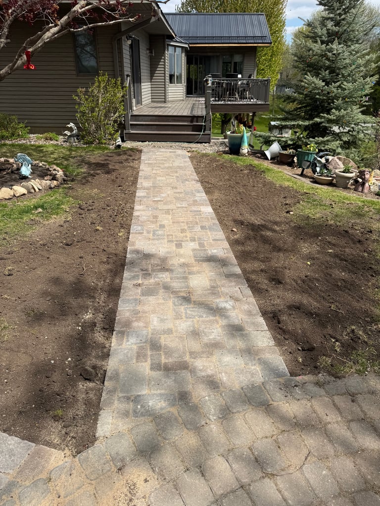 Newly installed paver walkway leading to modern cabin with freshly landscaped yard and garden beds